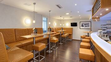 A modern restaurant interior with leather booths, bar stools, and pendant lighting.
