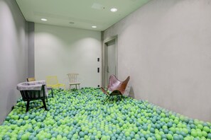 A room with a floor covered in green and blue balls, a door, and three chairs. - Seminaris Sunday Hotel Bad Honnef (Bad Honnef)