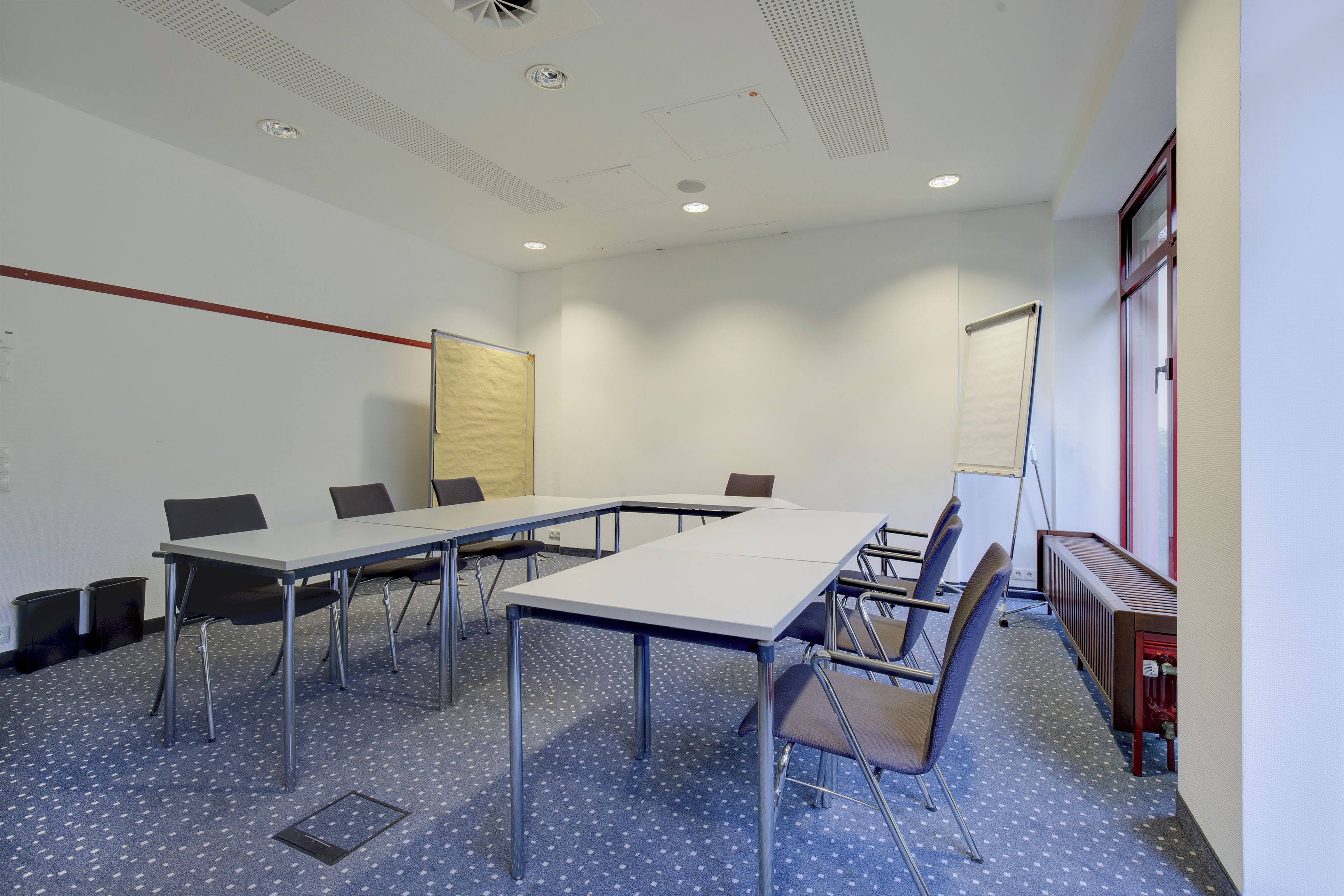 A conference room with a long table, chairs, a whiteboard, and a projector screen.