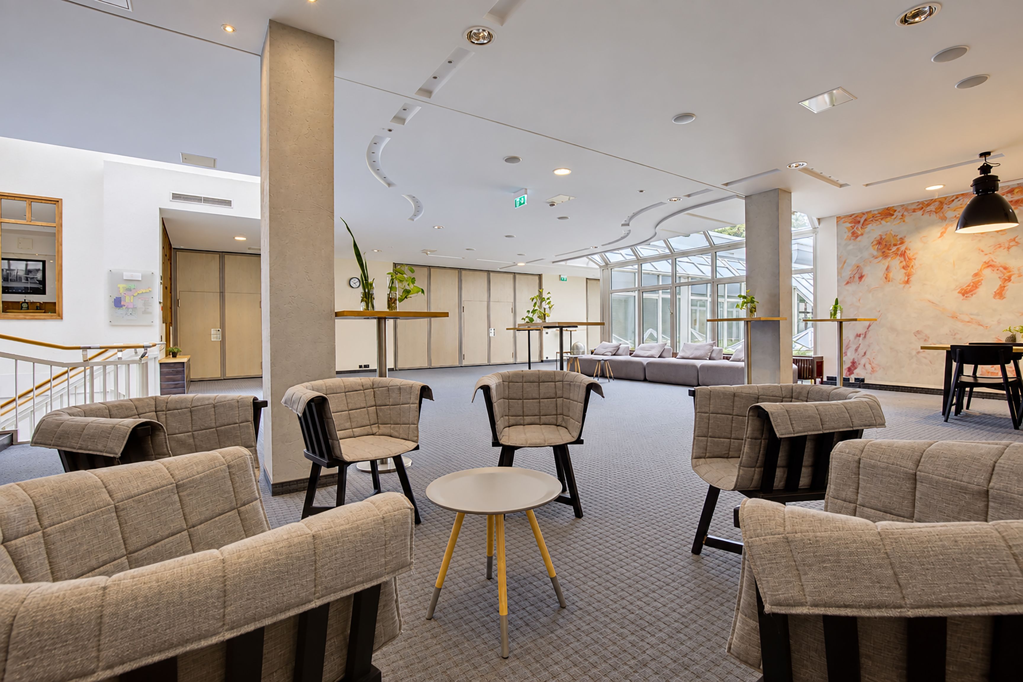 A modern interior with seating areas, a staircase, and a large window.