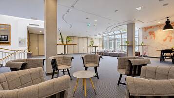 A modern interior with seating areas, a staircase, and a large window.