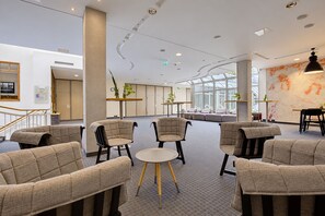 A modern interior with seating areas, a staircase, and a large window. - Seminaris Sunday Hotel Bad Honnef (Bad Honnef)