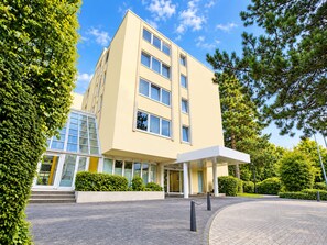 A modern hotel building with a flat facade, multiple windows, and a covered entrance area. - Seminaris Sunday Hotel Bad Honnef (Bad Honnef)