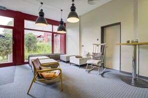 A hotel room with a bed, a chair, a table, and a window with a view of greenery. - Seminaris Sunday Hotel Bad Honnef (Bad Honnef)