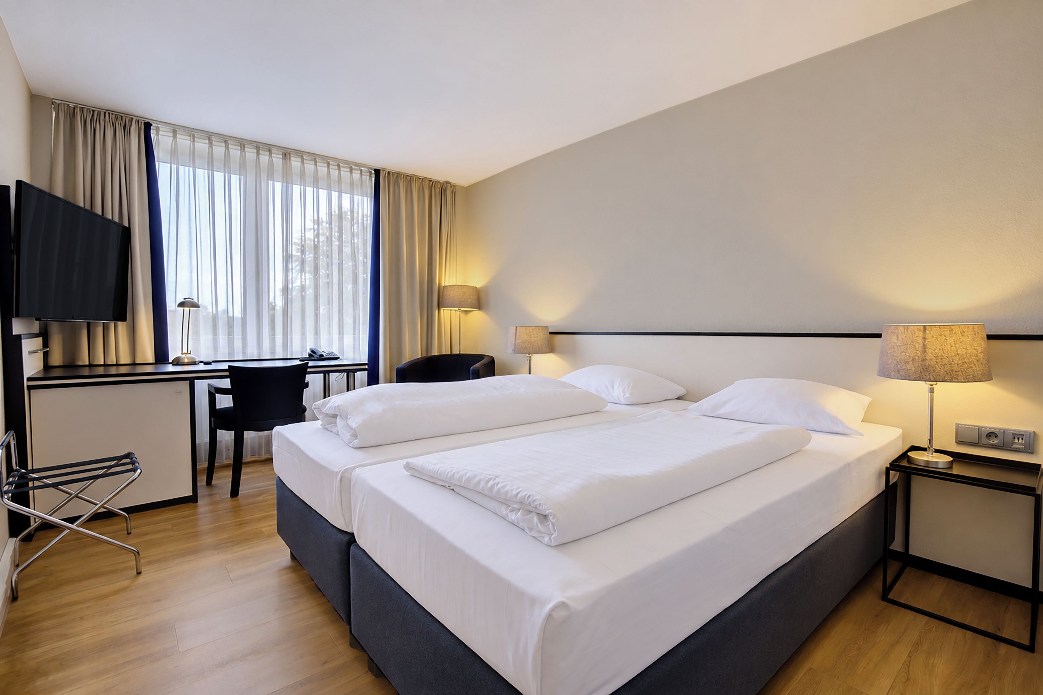 Een hotelkamer met een bed, bureau, stoel, televisie en lampen.