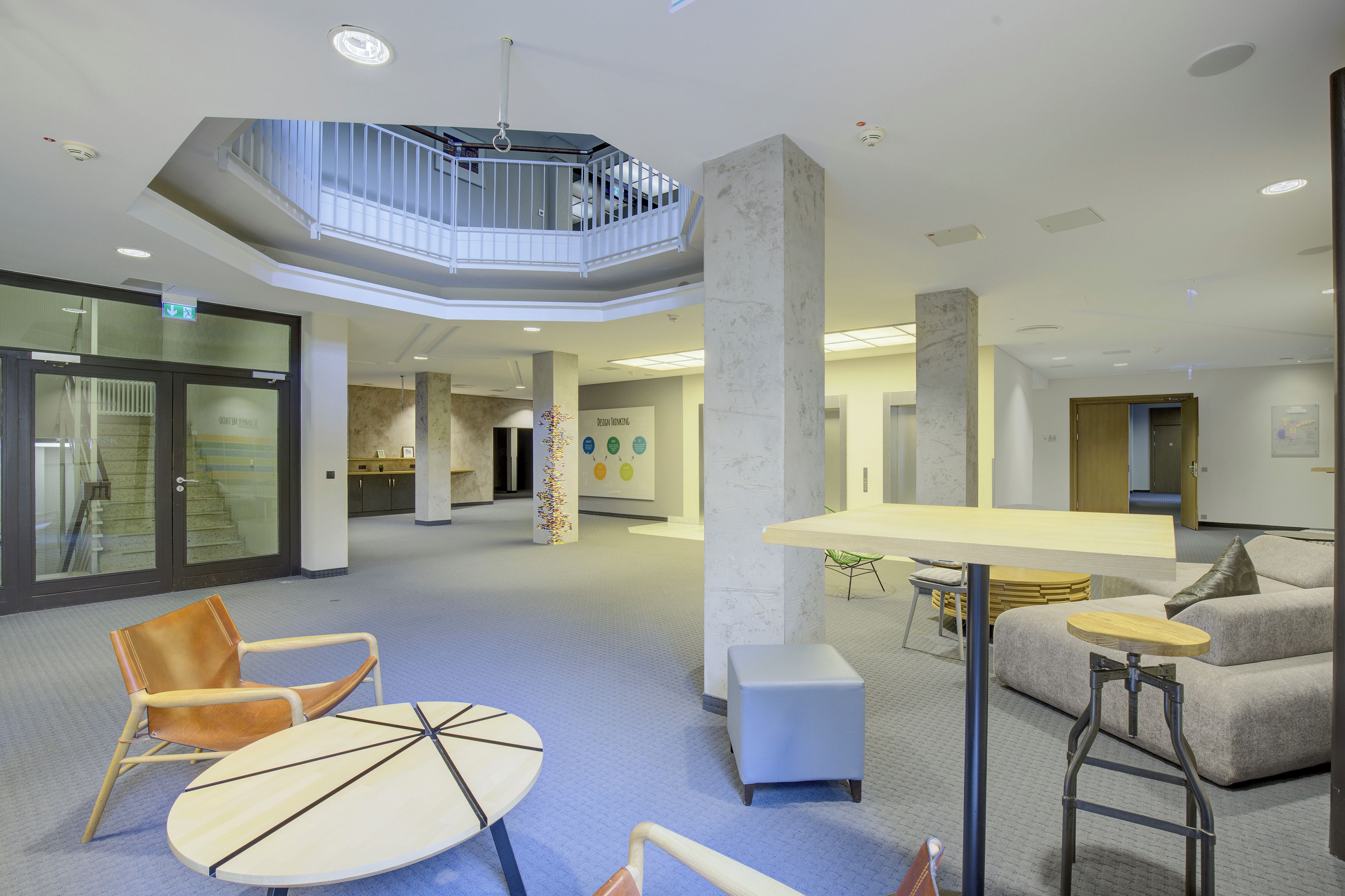 En modern inredning med en central sittgrupp, en trappa och ett entresolplan.