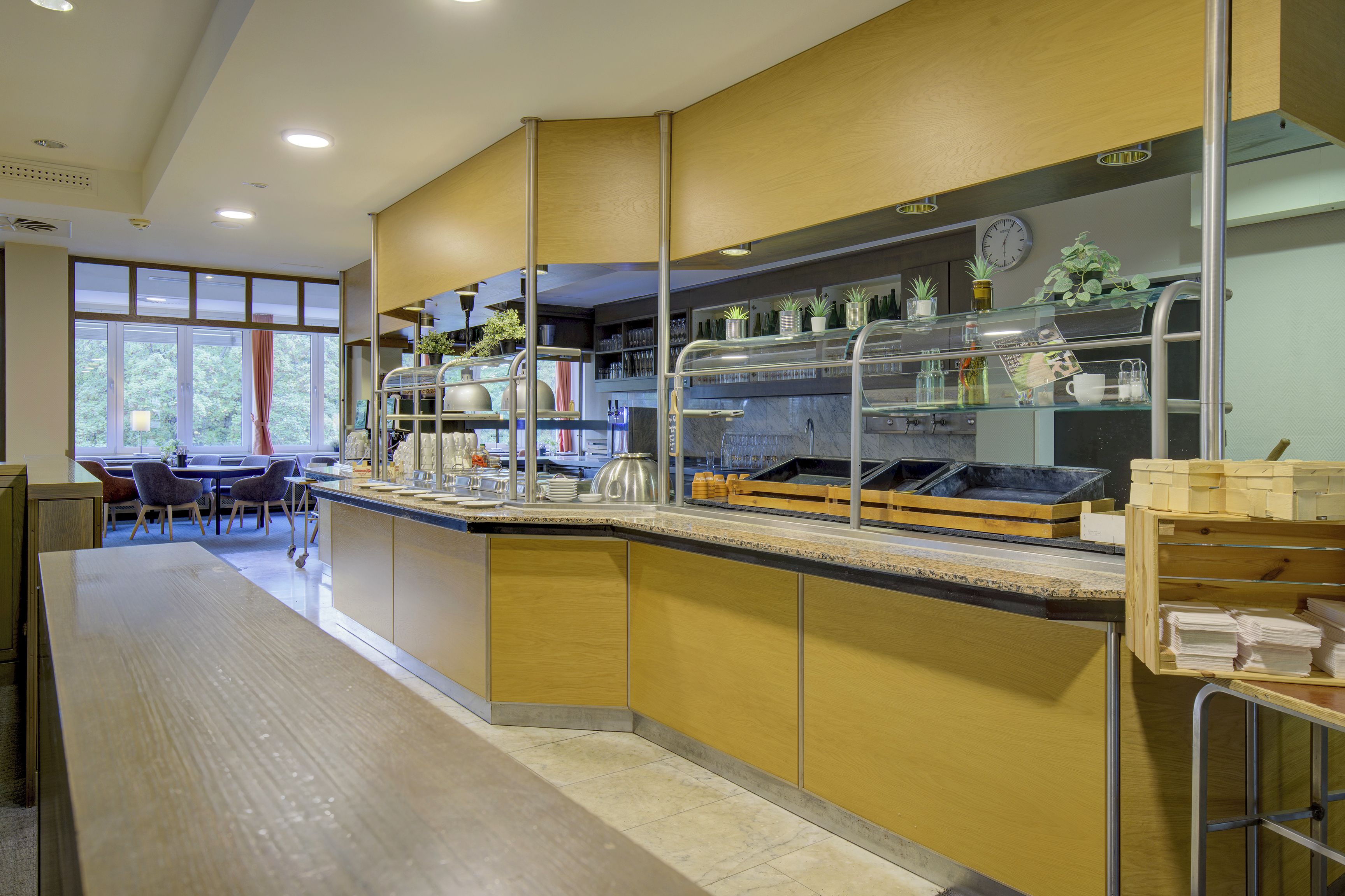 A modern kitchen area with a counter, various kitchen appliances, and a seating area with tables and chairs.