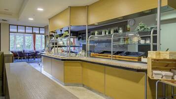 A modern kitchen area with a counter, various kitchen appliances, and a seating area with tables and chairs.