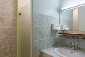 Un baño con lavamanos, espejo y secamanos.