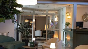 A modern lobby with a checkered floor, seating areas, and a wooden ceiling. - The Originals City, Le Patio, Cholet Nord (Beaupreau-en-Mauges)