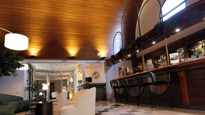 A bar area with a checkered floor, a reception desk, and a seating area with chairs and a sofa. - The Originals City, Le Patio, Cholet Nord (Beaupreau-en-Mauges)