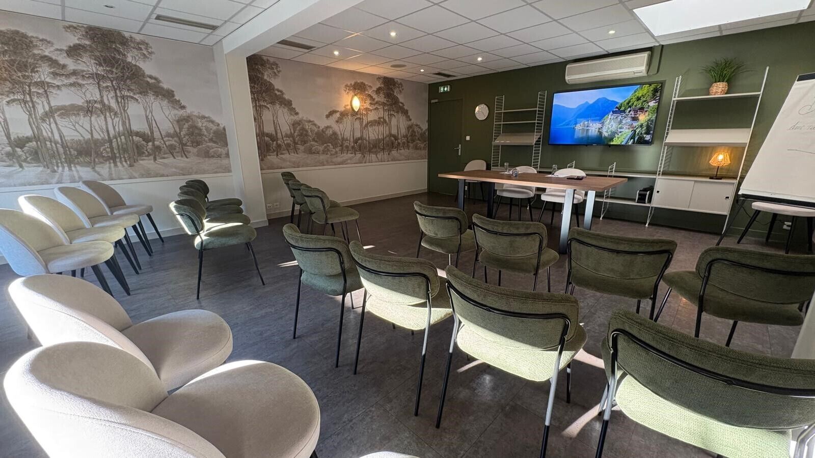 A conference room with a large screen, chairs, and a table.