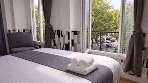 Habitación de hotel con cama, vistas al exterior y cortinas en la ventana.