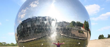 A large reflective sphere with a person standing in front of it.
