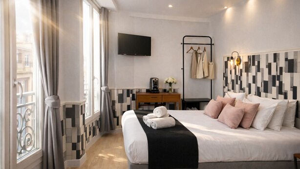 Habitación de hotel moderna con una cama grande, un escritorio, un televisor y vistas a la ciudad.