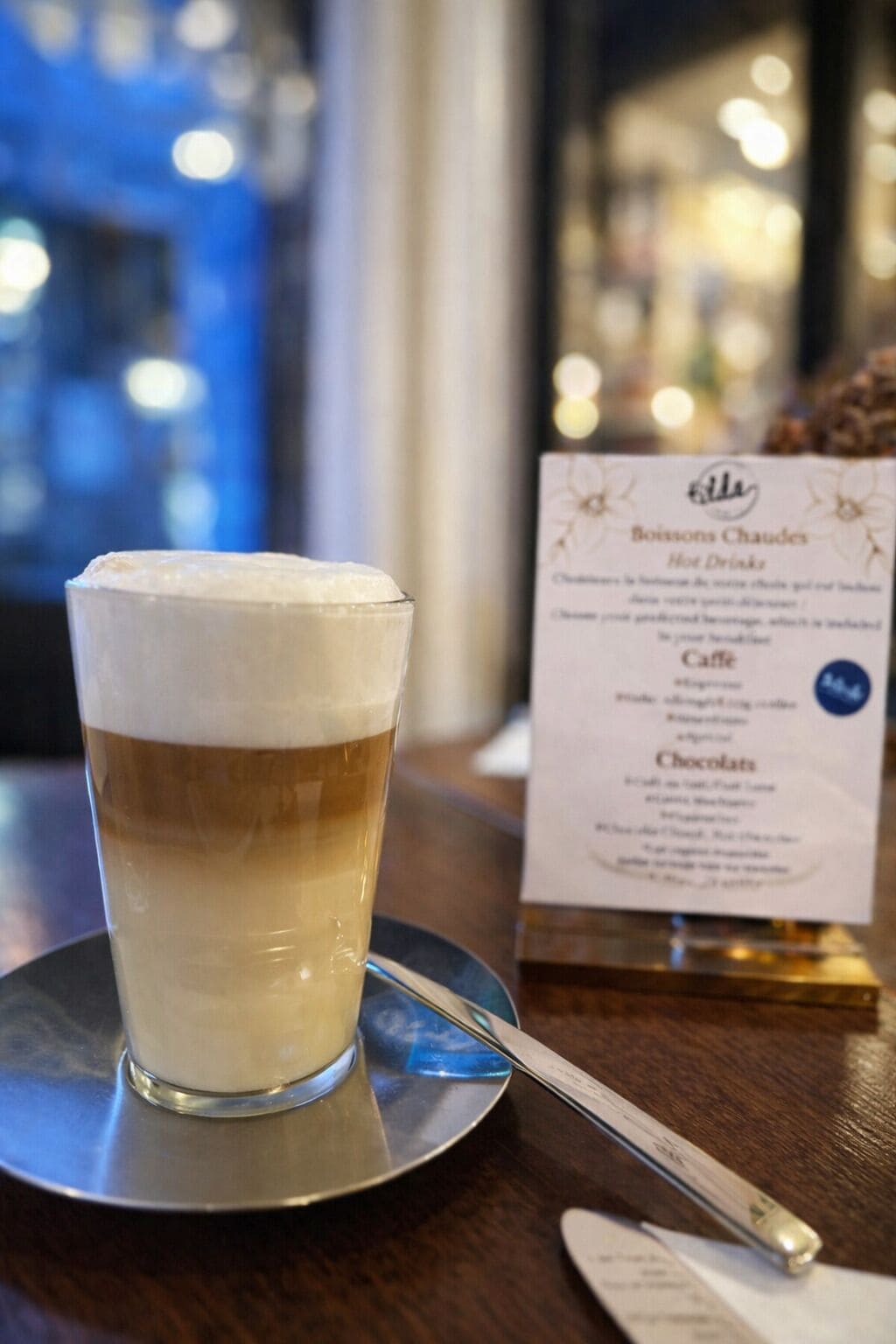 A glass of layered beverage on a coaster with a menu in the background.