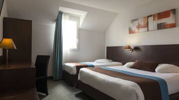 Ein Hotelzimmer mit zwei Betten, einem Schreibtisch, einer Lampe und einem Vorhangfenster.