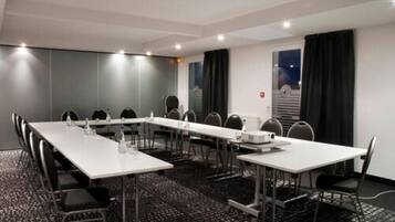 A conference room with a long table, chairs, a projector, and a carpeted floor.