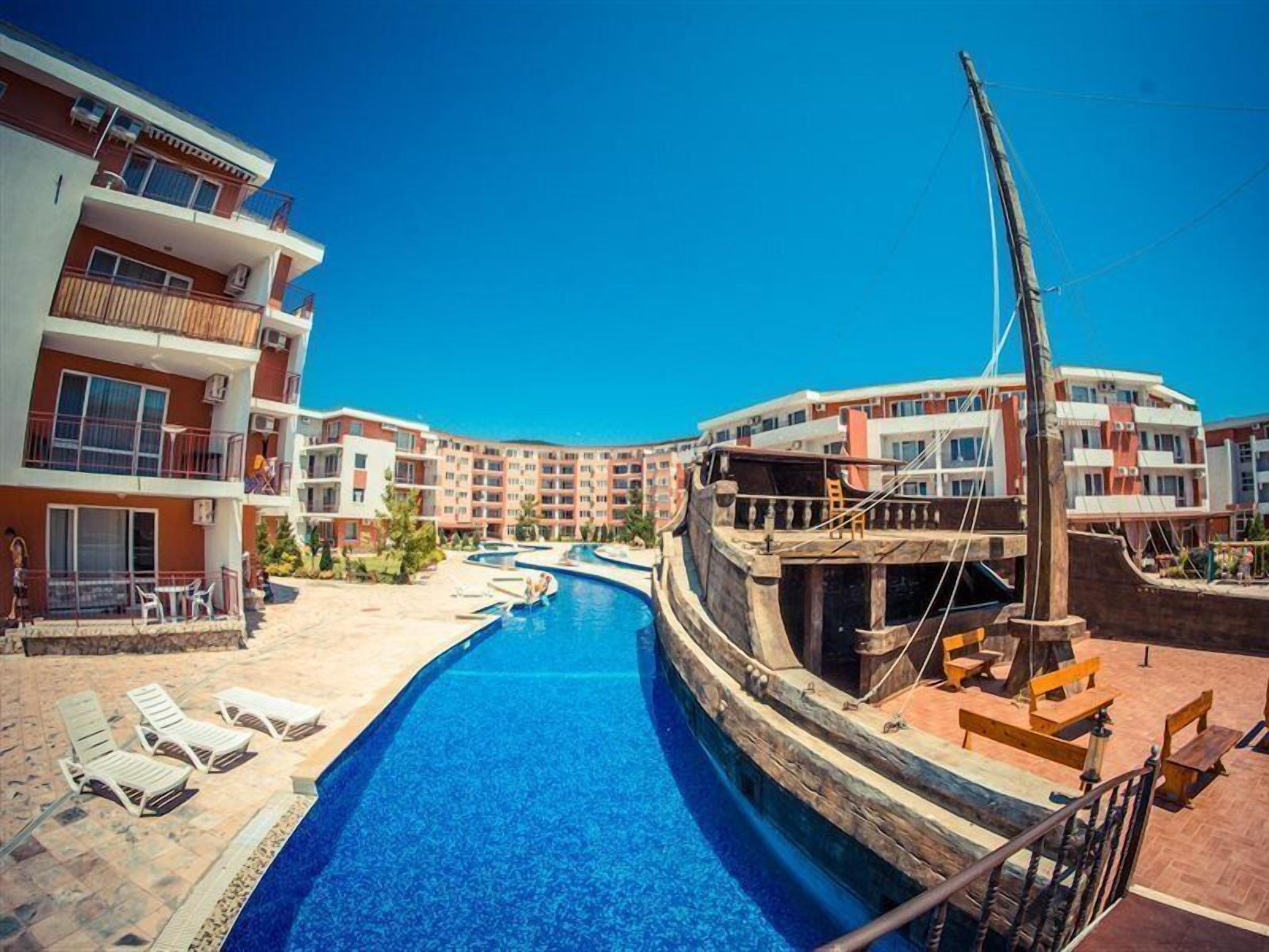 Een buitenzwembad, parasols bij het zwembad en ligstoelen