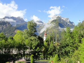 A serene landscape with a mountain backdrop, a white building with a red roof, and lush greenery. - Haus Patricia (Lofer)
