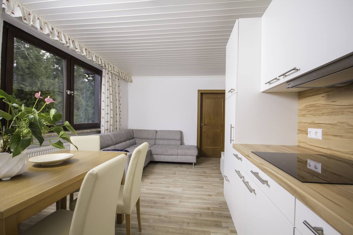 Uma cozinha moderna com bancada de madeira, forno embutido e um espaço de refeições com mesa e cadeiras.