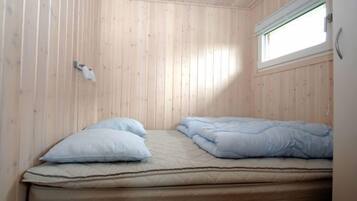 A small, single-bed room with wooden walls and a window.
