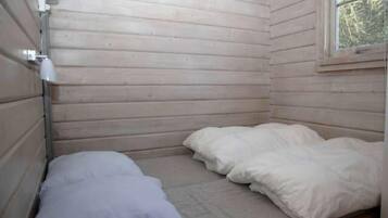 A small, single-bed room with wooden walls and a window.