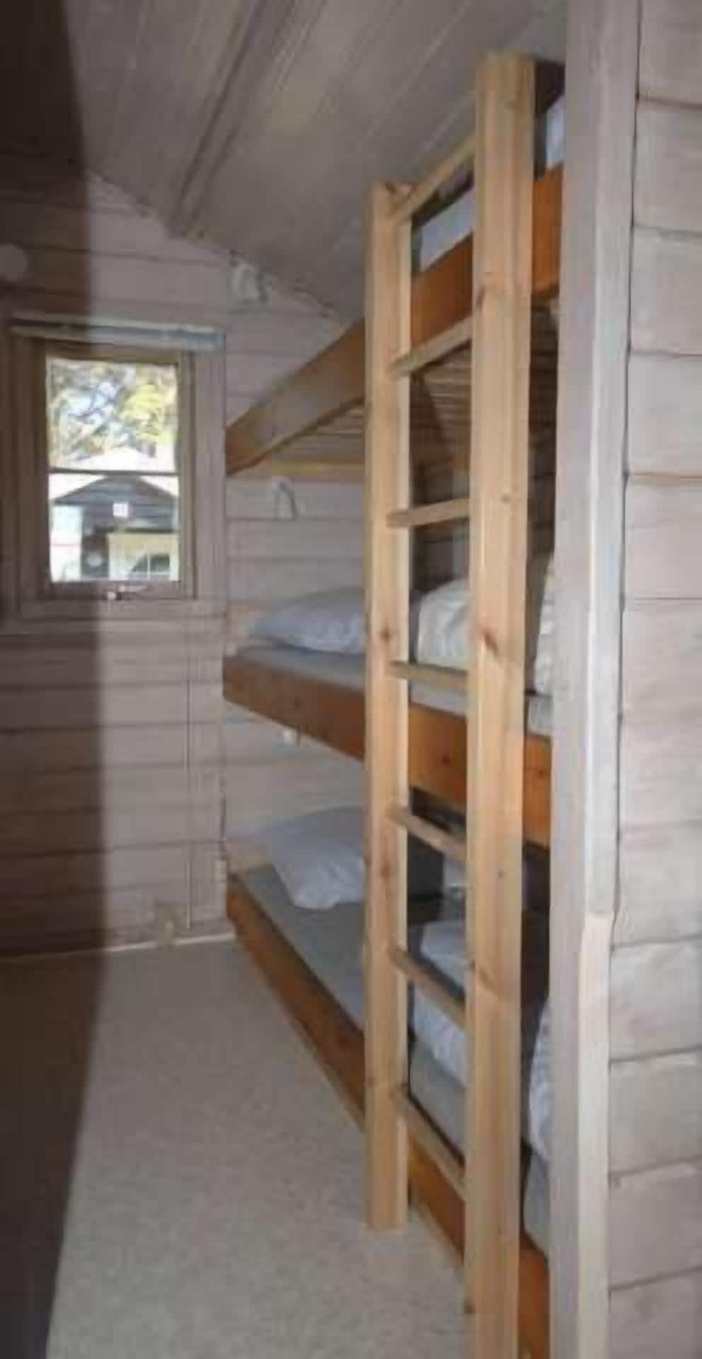 Habitación con literas, paredes de madera y ventana.
