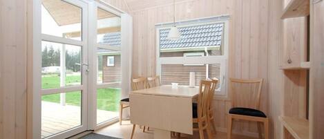 A wooden-paneled room with a table and chairs, a window with a view of the outdoors, and a door leading outside.