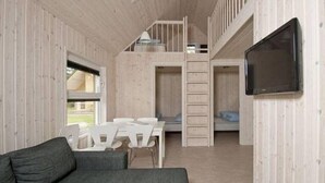 Habitación pequeña con una cama litera, una mesita y un sofá.