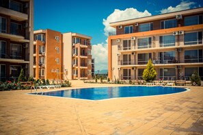 Ein moderner Apartmentkomplex mit Schwimmbad, Balkonen und Klimaanlagen.