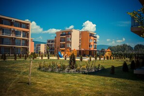 Ein mehrstöckiges Wohngebäude mit Balkonen, einem Spielplatz und einem angelegten Garten.