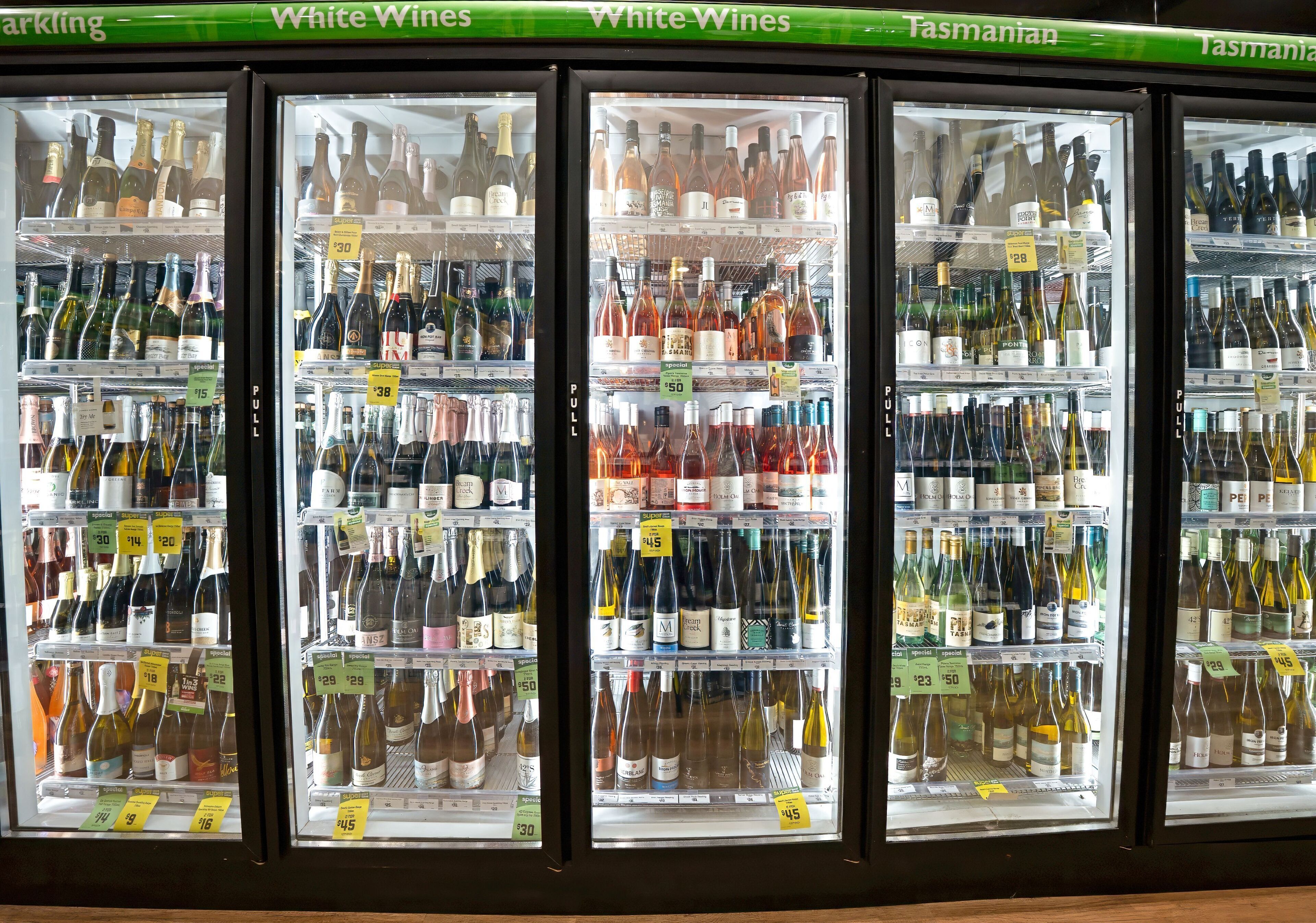 Vitrina refrigerada con varias botellas de vino, cada una con su etiqueta de precio.