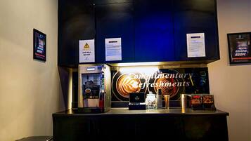 A coffee machine and a coffee cup on a counter with a warning sign above.