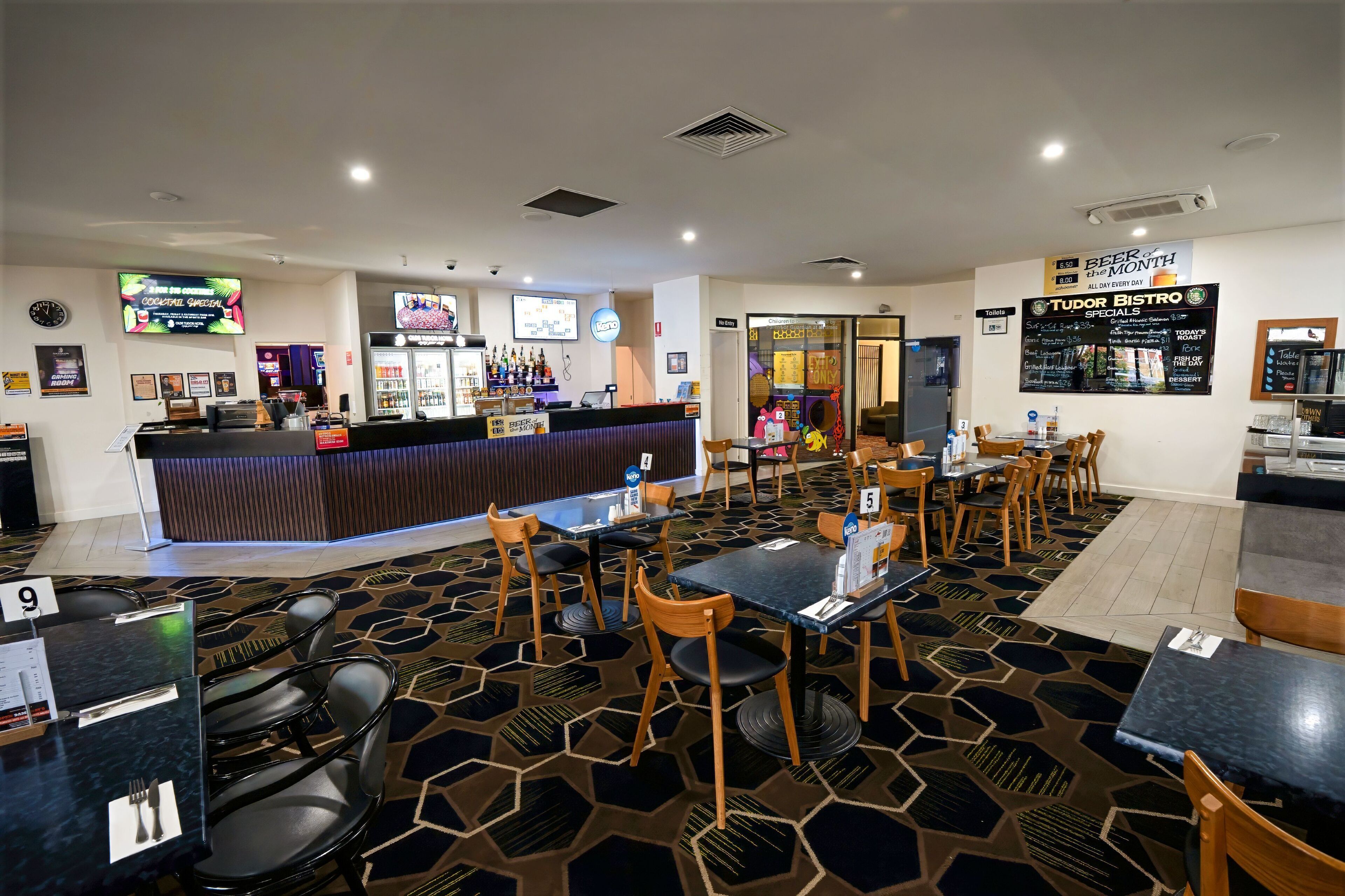A restaurant with a bar area, multiple tables, and chairs.