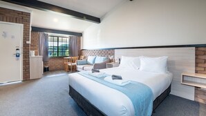 Une chambre d’hôtel avec un grand lit, un bureau et une fenêtre avec des rideaux.