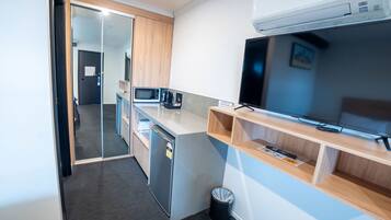 Una kitchenette compacta con microondas, cafetera y refrigerador pequeño.