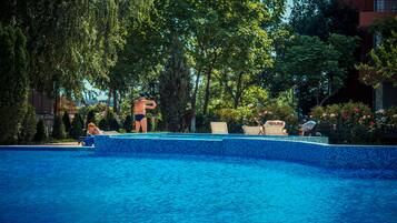 Relax by the pool surrounded by lush trees and a serene atmosphere.