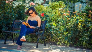 A person sitting on a bench in a garden with various plants and flowers. - Riviera Fort Beach (Ravda)