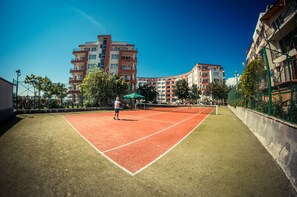 An outdoor tennis court surrounded by apartment buildings.