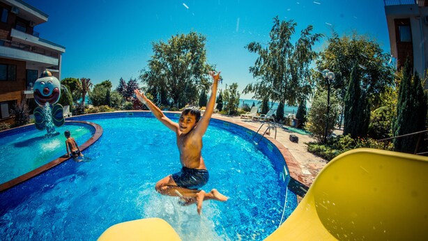 A swimming pool with a water slide and a person jumping into the water. - Messambria Fort Beach (Elenite)