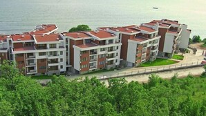 A multi-story apartment building with balconies, a paved driveway, and a view of the water. - Messambria Fort Beach (Elenite)