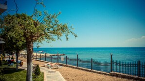 A beach with a fenced walkway, a tree, and a clear view of the sea. - Messambria Fort Beach (Elenite)