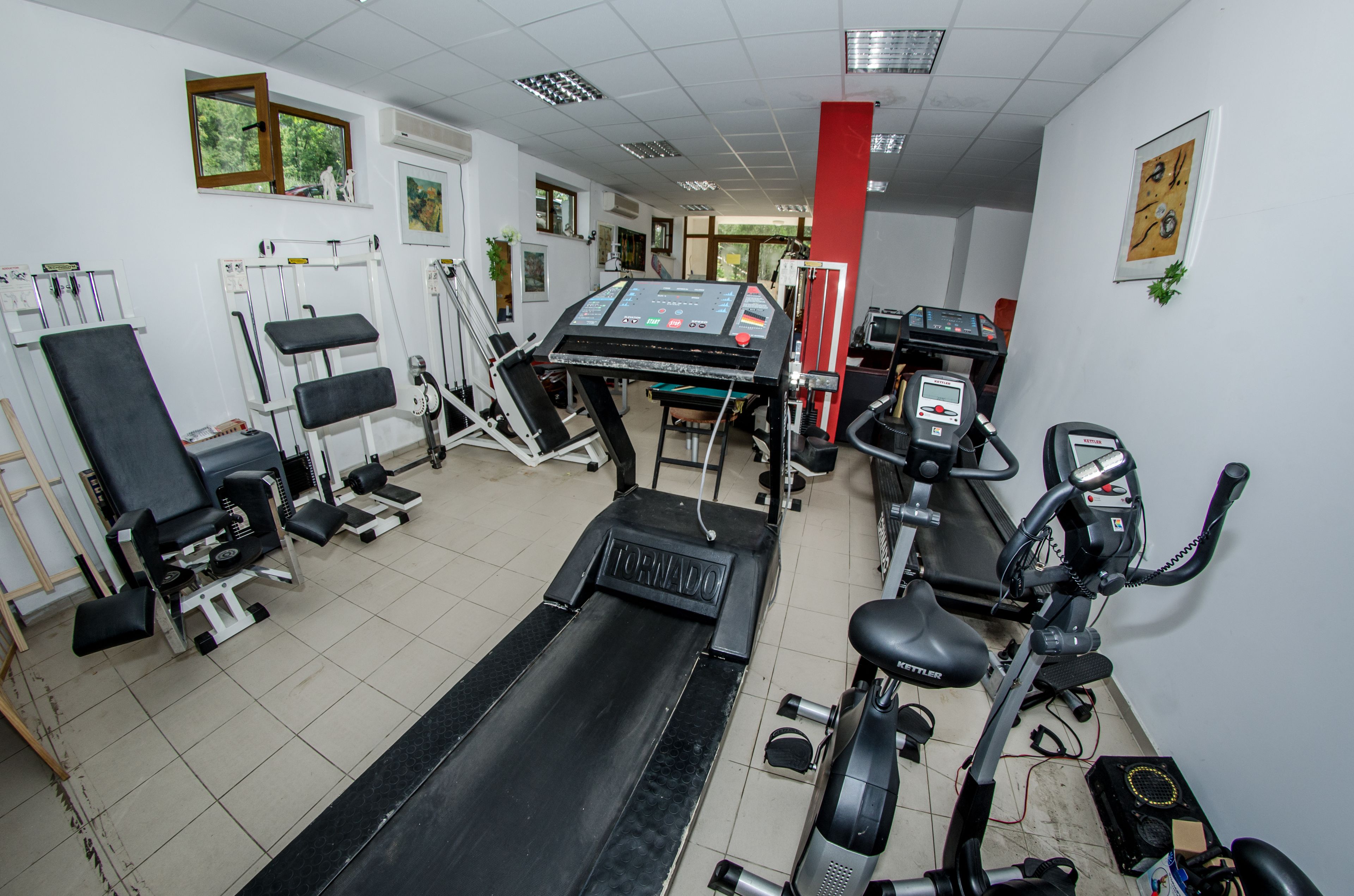 A gym with various exercise equipment including treadmills, stationary bikes, and weight machines.