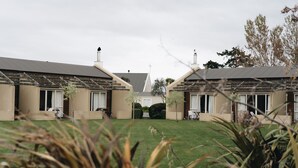 A courtyard with two buildings, each with a covered patio and a lawn in the center.