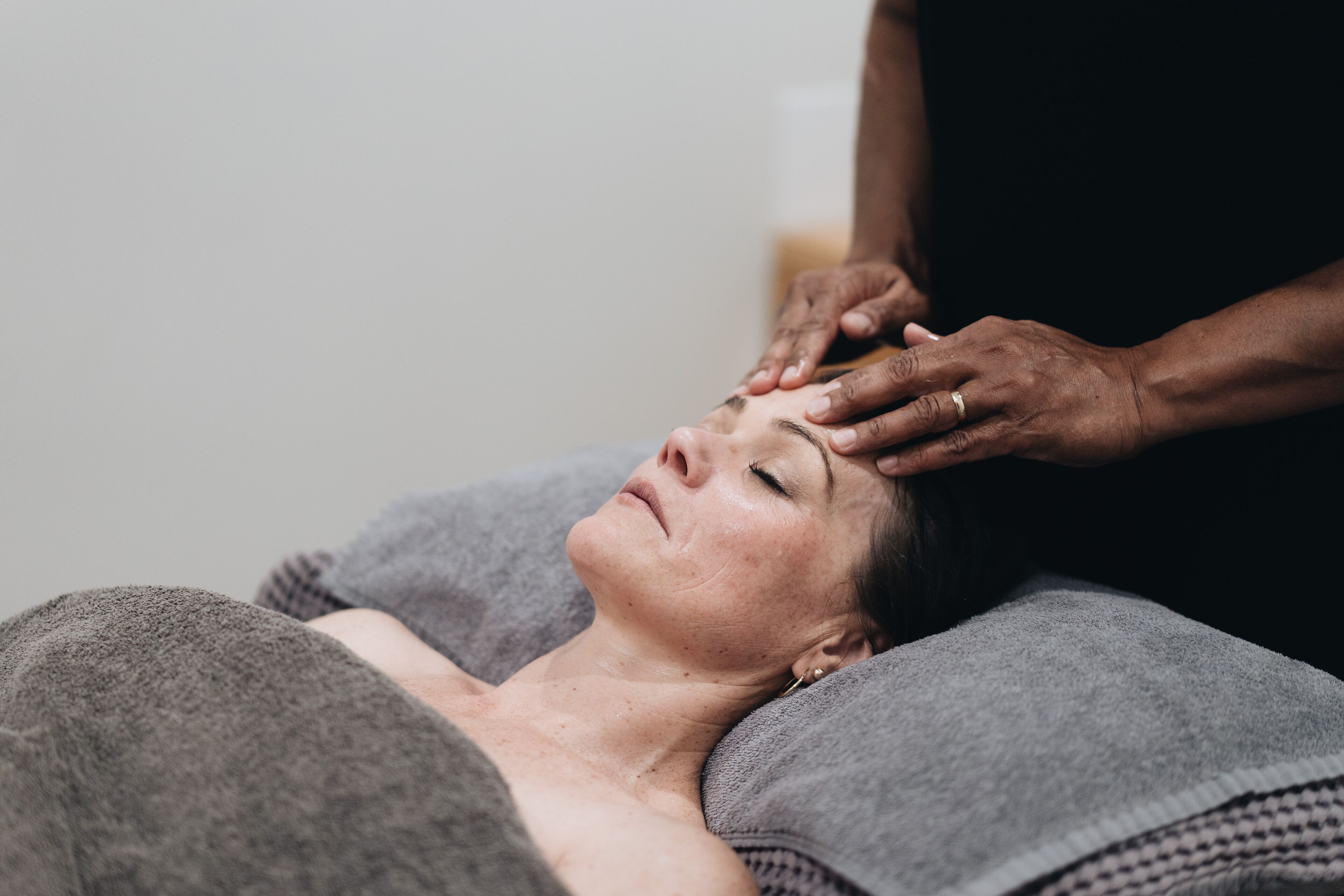 Une personne allongée, la tête couverte d’une serviette, qui reçoit un massage.