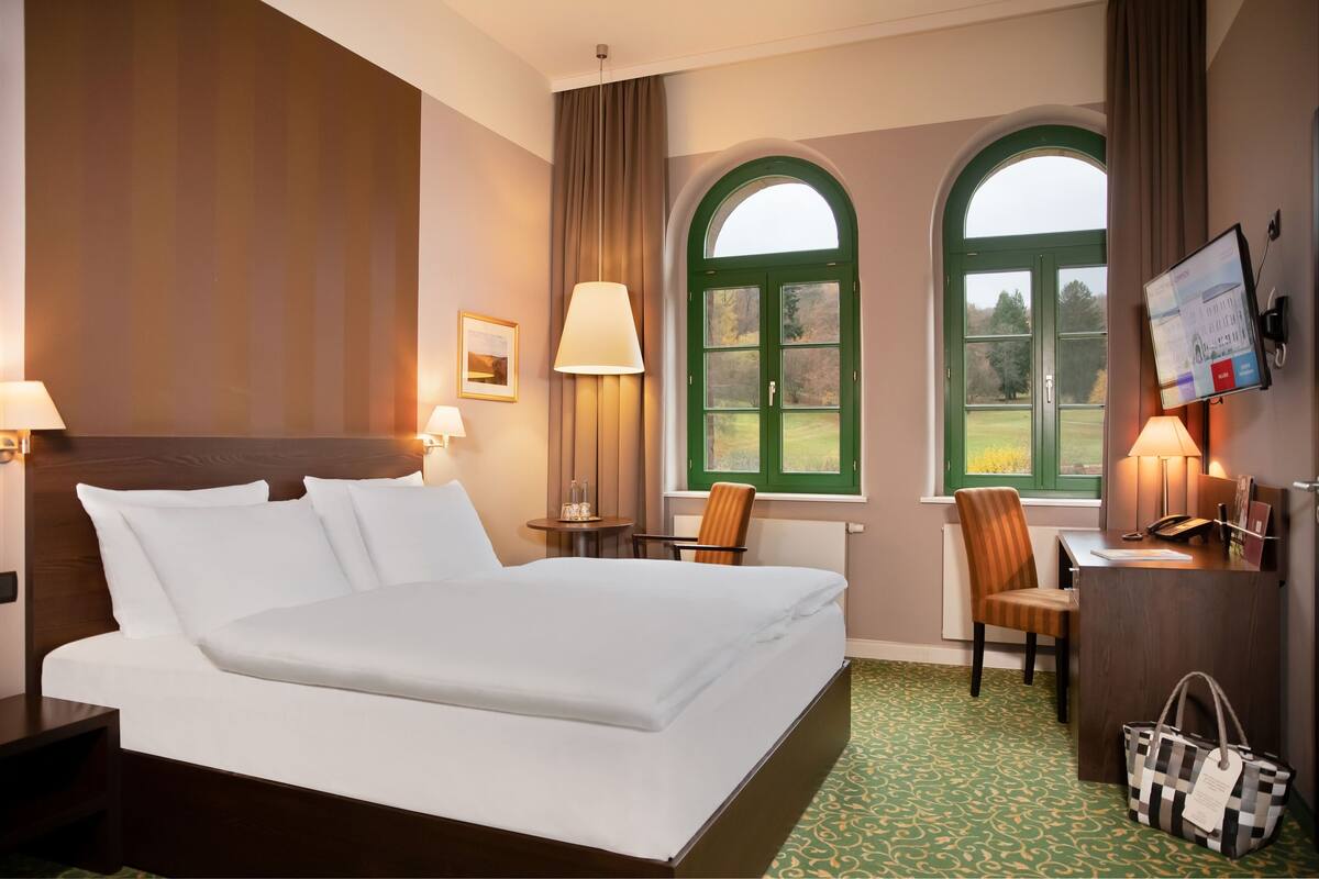 Habitación de hotel con una cama grande, dos sillones, un escritorio y una televisión.