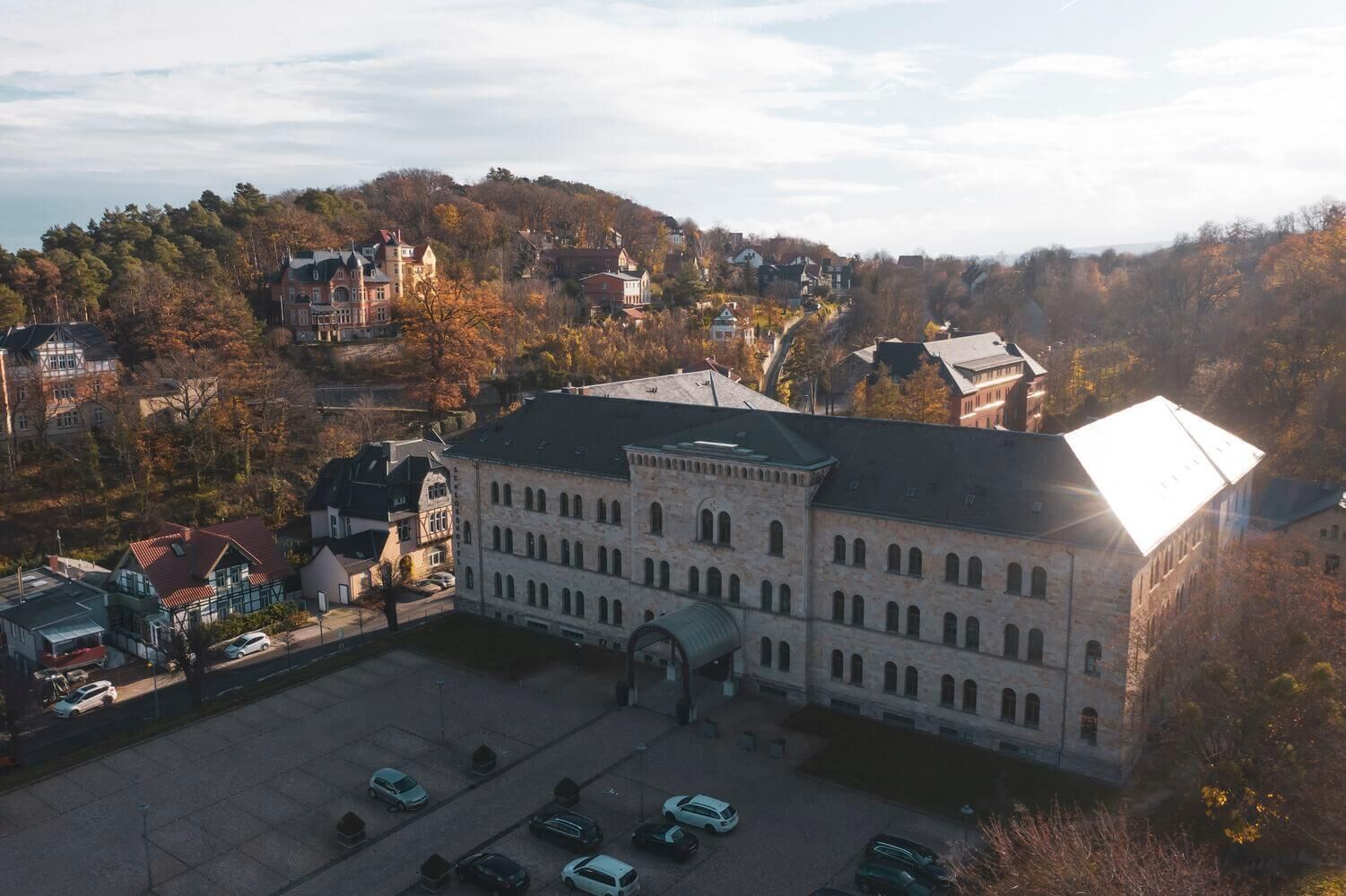 A large building with a central courtyard, surrounded by parked cars and trees.