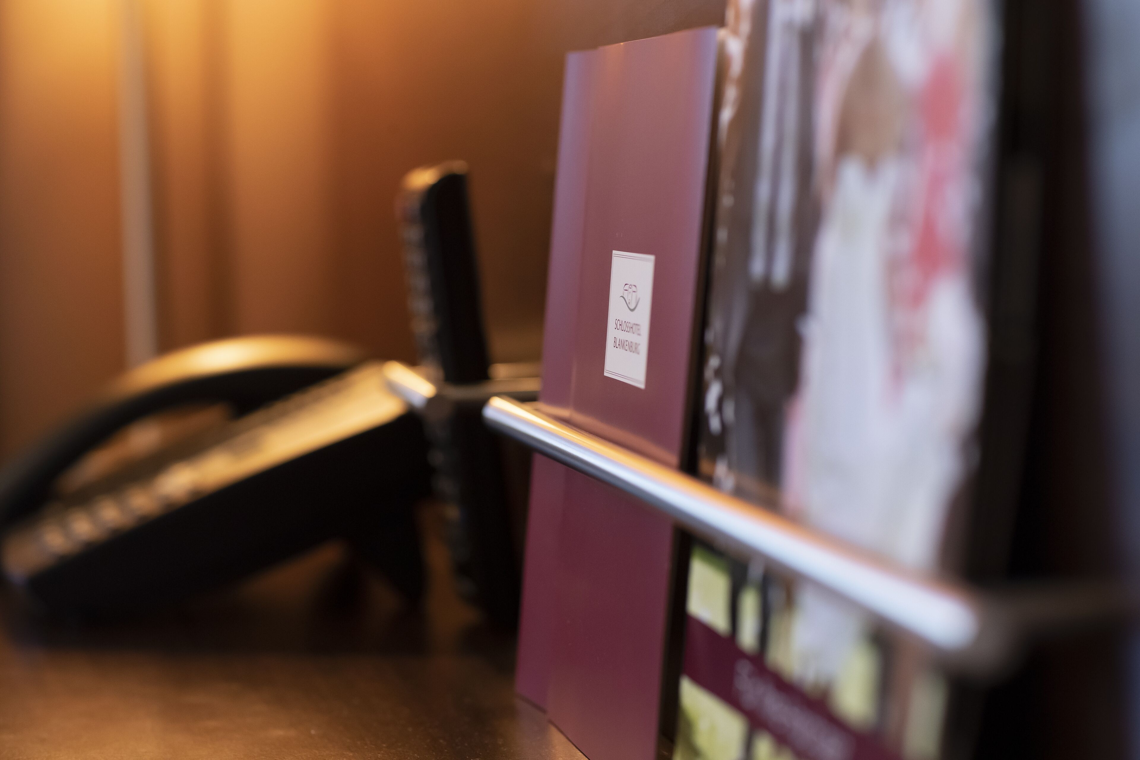 A close-up of a telephone and a red folder with a label on a desk.
