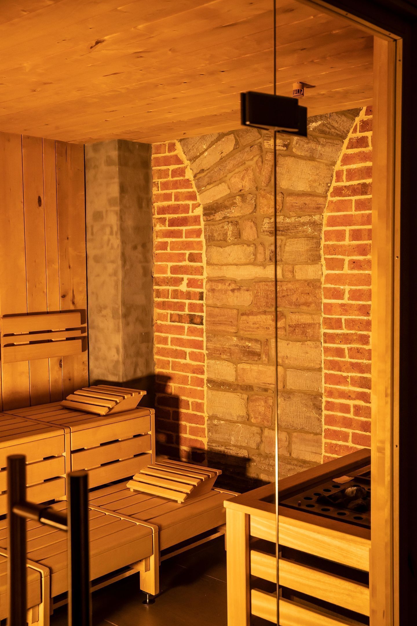 Un sauna con bancos de madera y pared de ladrillo.